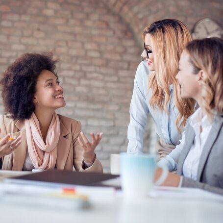 three woman talking at a desk
